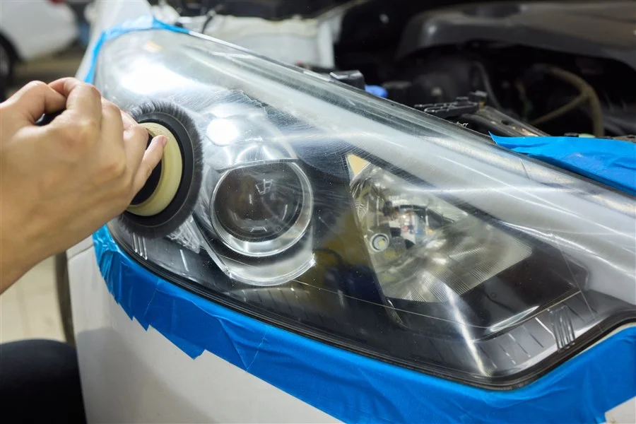 Headlight lens masked with tape and machine polished during a headlight restoration